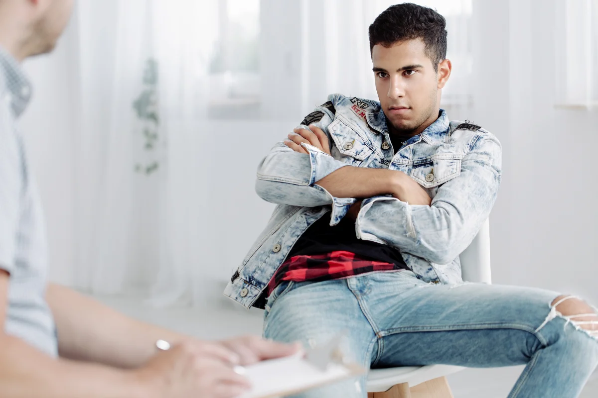 Adolescente rebelde con actitud desafiante durante una sesión con un psicólogo, ilustrando cómo actuar con hijos adolescentes rebeldes